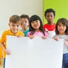 - diversity children holding blank poster in classroom at kindergarten - Diversity Equity and Inclusion in STEM | Manifezt Foundation Diversity children holding blank poster in classroom at kindergarten